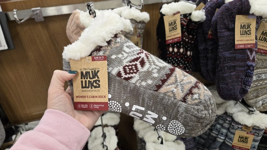 womans hand holding a pair of mukluks slipper socks