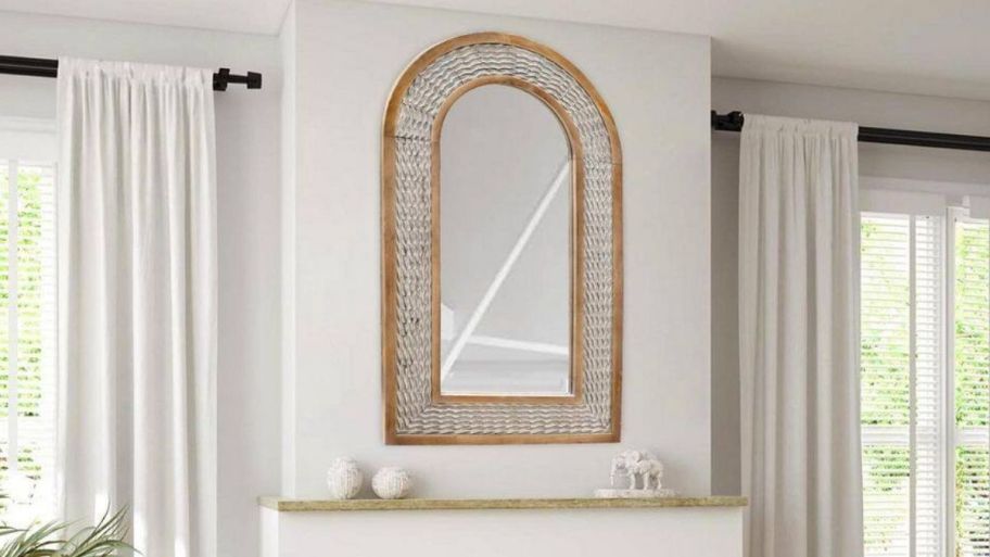 arched wooden wall mirror hanging above a mantle