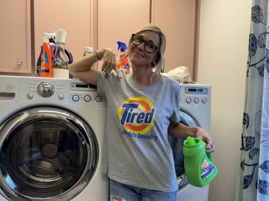 woman in a gray tshirt holding a bottle of laundry detergent