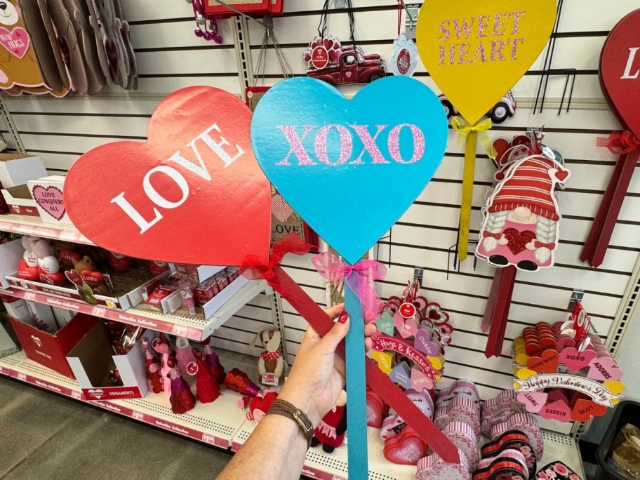 womans hand holding heart-shaped yard signs