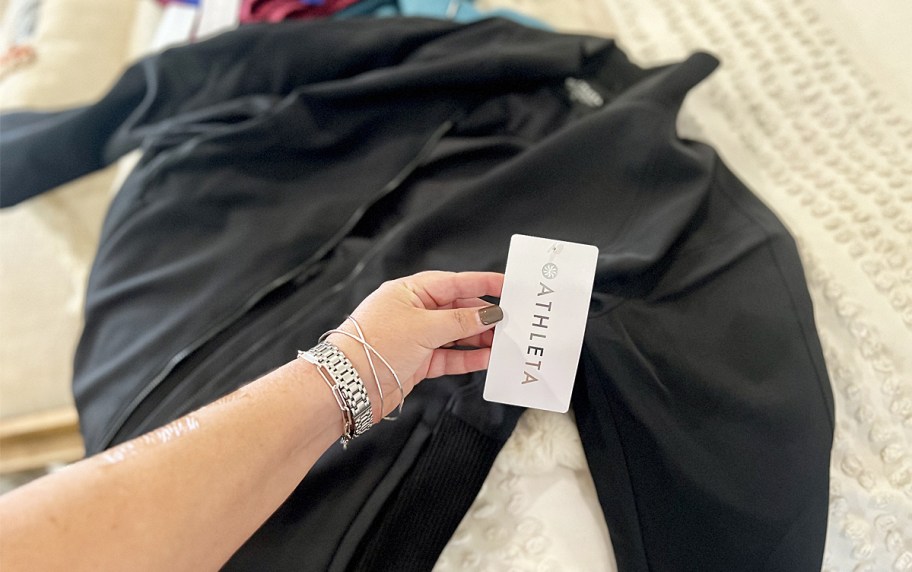 hand holding the tag to a black athleta jacket