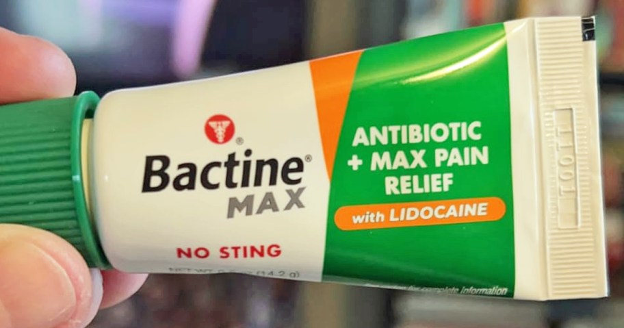 hand holding a green and white tube of Bactine MAX Antibiotic + Pain Relief Ointment