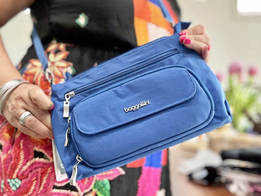 woman holding up a blue crossbody bag