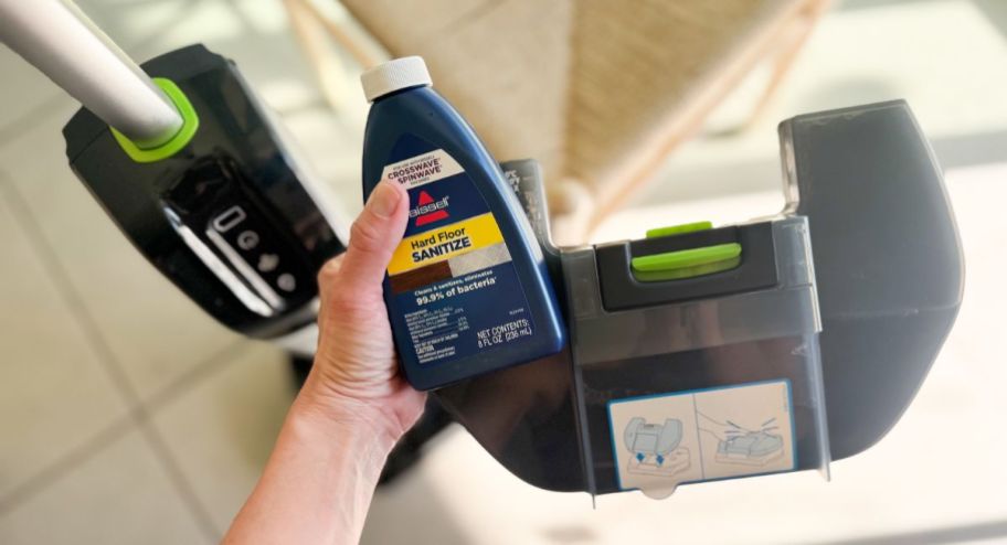 hand holding Bissell-vacuum with cleaner it comes with