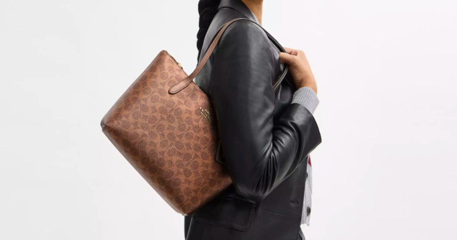 Woman carrying brown coach bag on shoulder