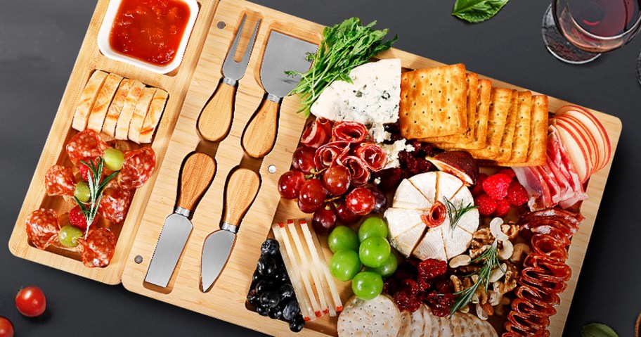 bamboo charcuterie board with cheeses, fruits, and crackers on it