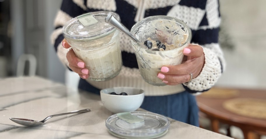 Woman holding up glass containers, filled with overnight oats