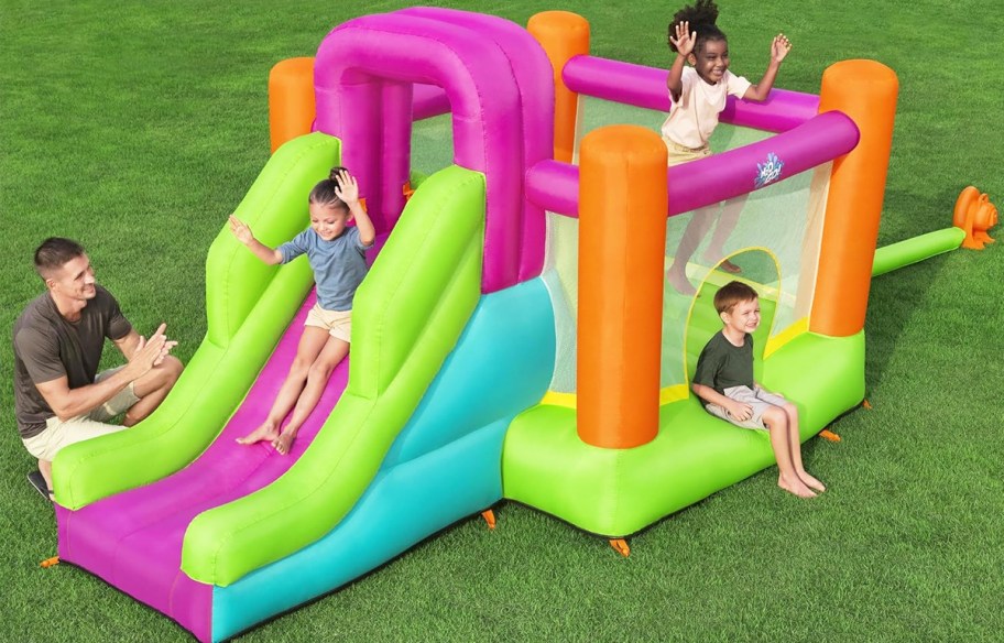 kids playing on a colorful inflatable bounce house with a slide