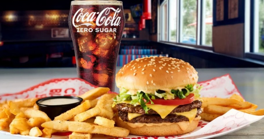 a cheeseburger, fries, and coca cola in a glass
