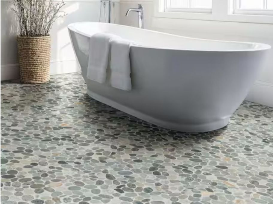A tub in a bathroom on a pebble floor