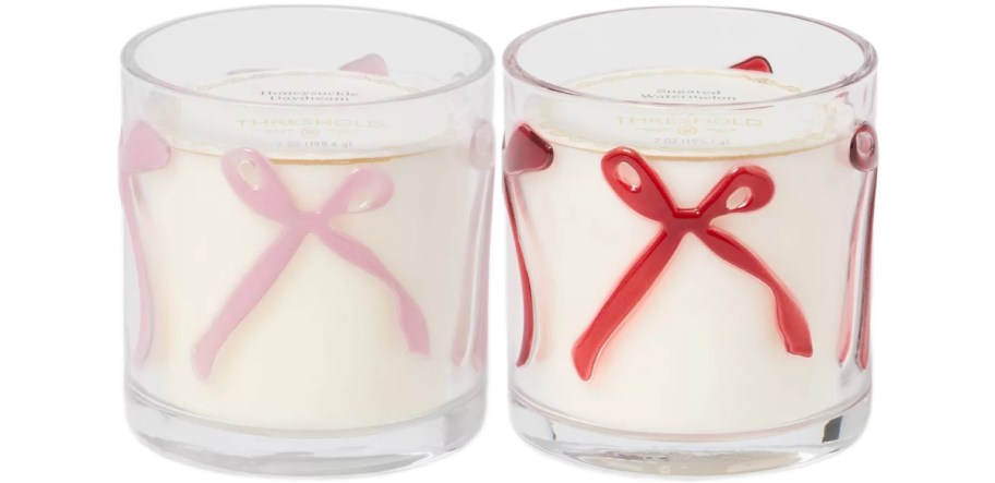 Two glass candles with bows on them. One is pink and one is red.