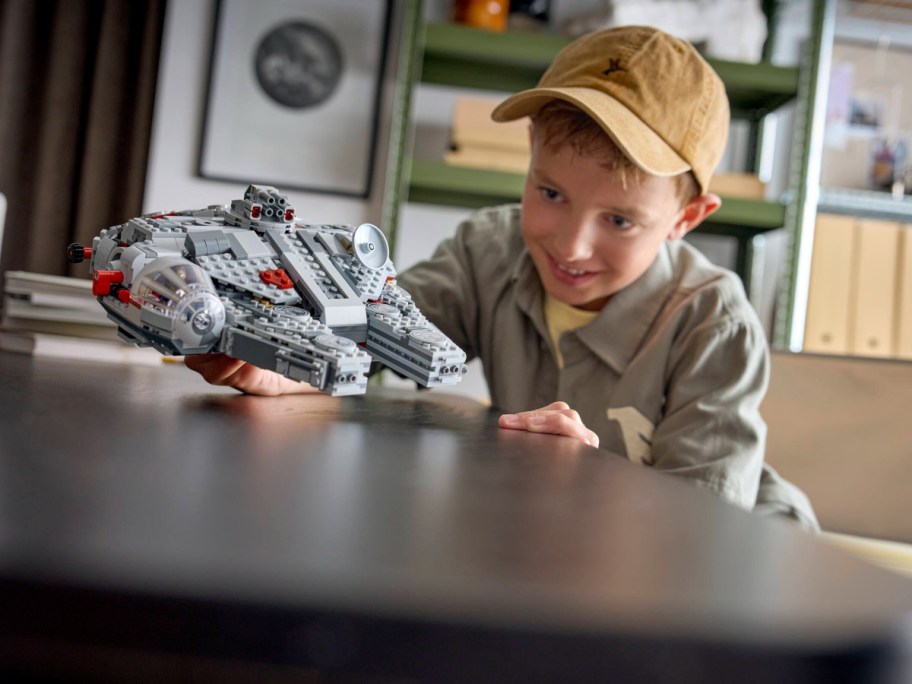 A kid playing with a LEGO Star Wars SMART Play: Millennium Falcon set all put together.