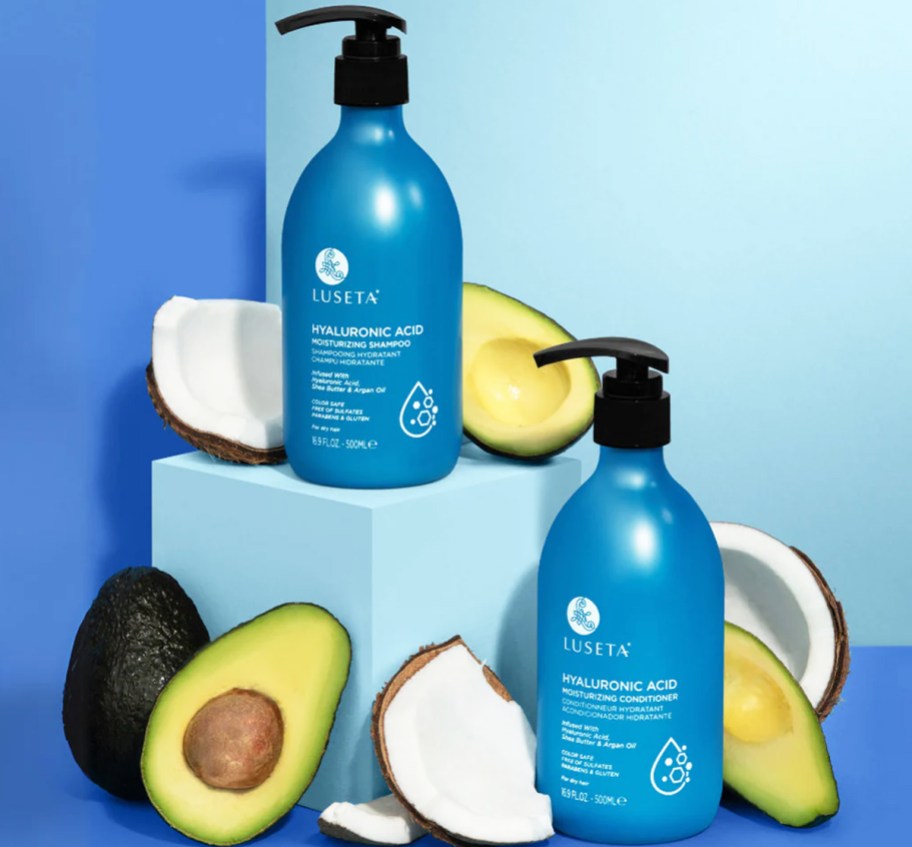 blue bottles of shampoo & conditioner with avocados and coconut pieces