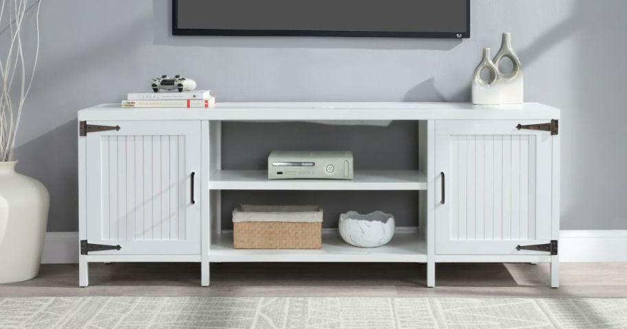 A white tv stand in a living room with a tv above it 