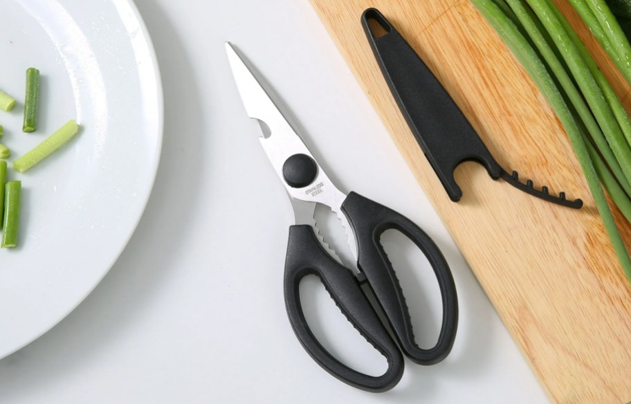 pair of kitchen scissors near cutting board with green onions