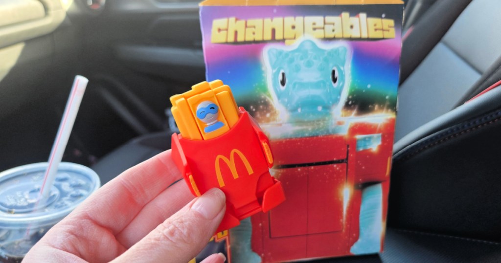 Woman holding a McDonald's changeable's meal toy inside restaurant