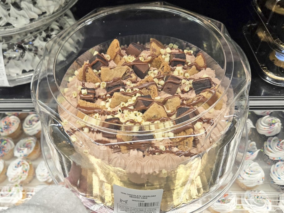 hand holding up a chocolate cake in store