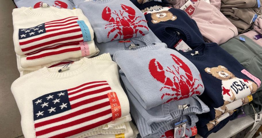 Several sweaters with American flags, lobsters, and Bears on them