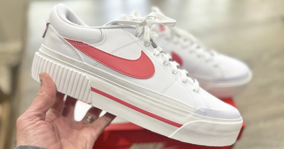 hand holding up white and pink platform nike sneakers