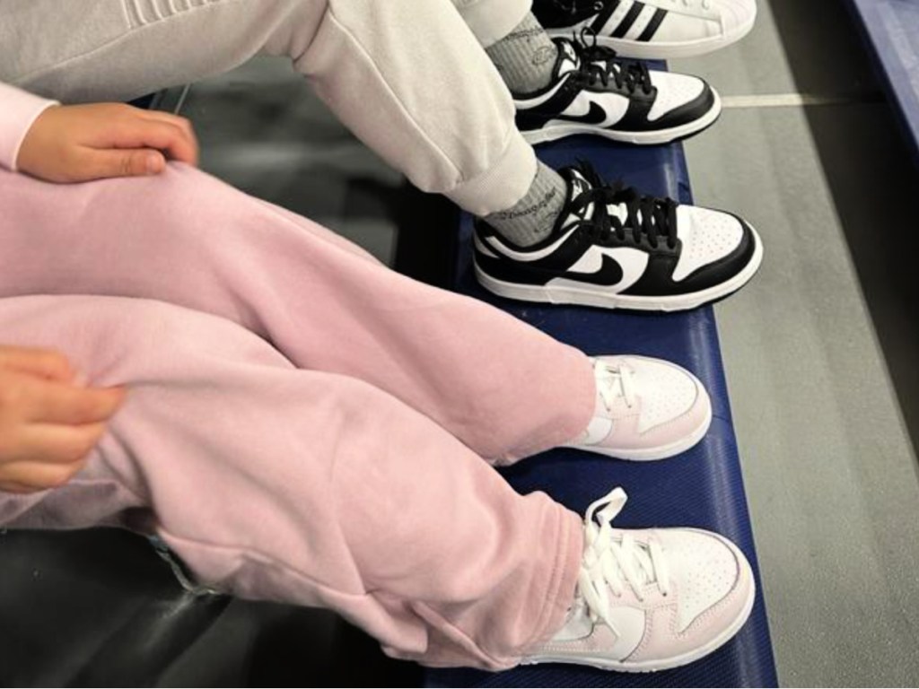 Two kids sitting on bleachers wearing Nike shoes