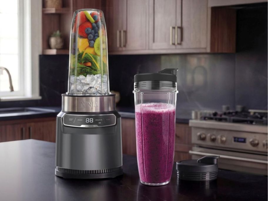 A Ninja Nutri-Blender Pro next to a blender cup filed with a purple smoothie