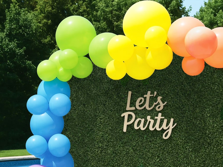 rainbow balloon garland on a green photo backdrop