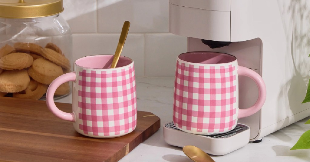 Pink gingham, coffee mugs on kitchen countertop next to coffee maker