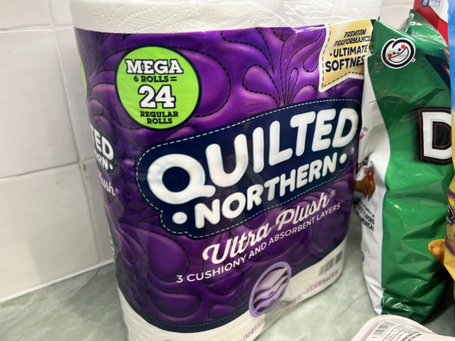 purple pack of Quilted Northern Ultra Plush Toilet Paper on counter near other groceries