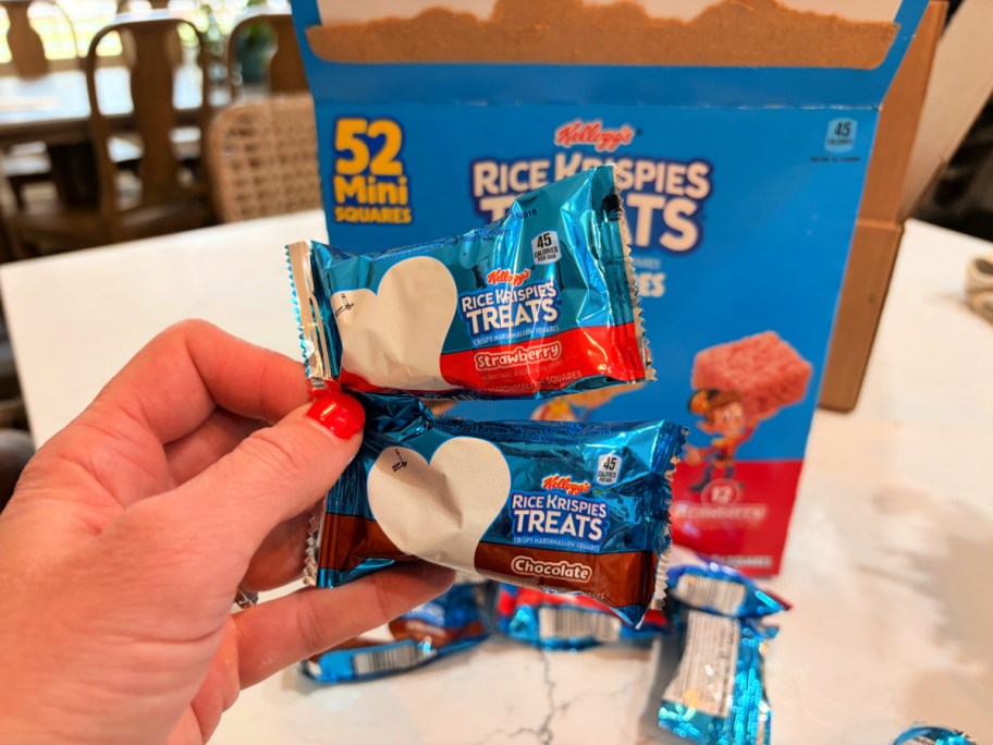 hand holding Rice Krispies Treats Mini Squares with a box of them behind it