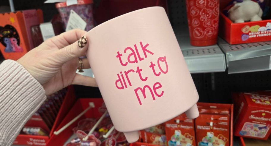 hand holding Talk dirt to me planter in front of a store display