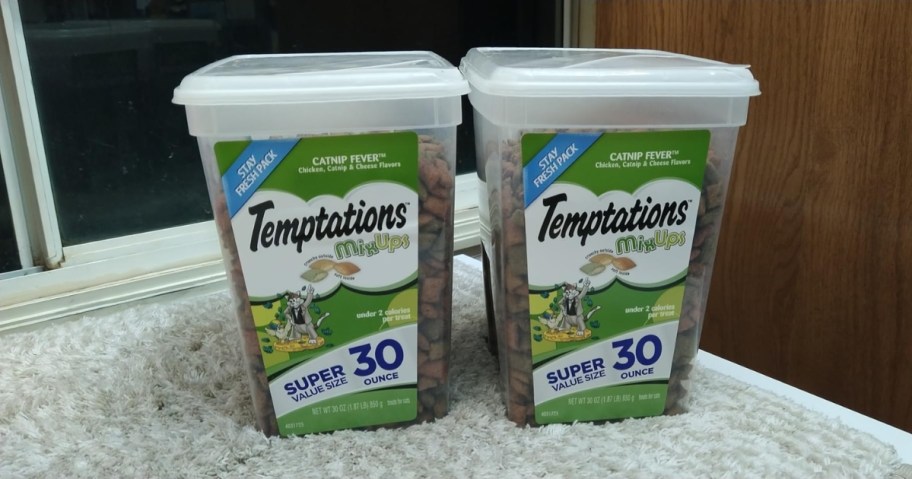two tubs of temptations mixups cat treats on carpet