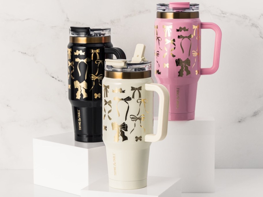 Three insulated tumblers with decorative designs in black, pink, and white.