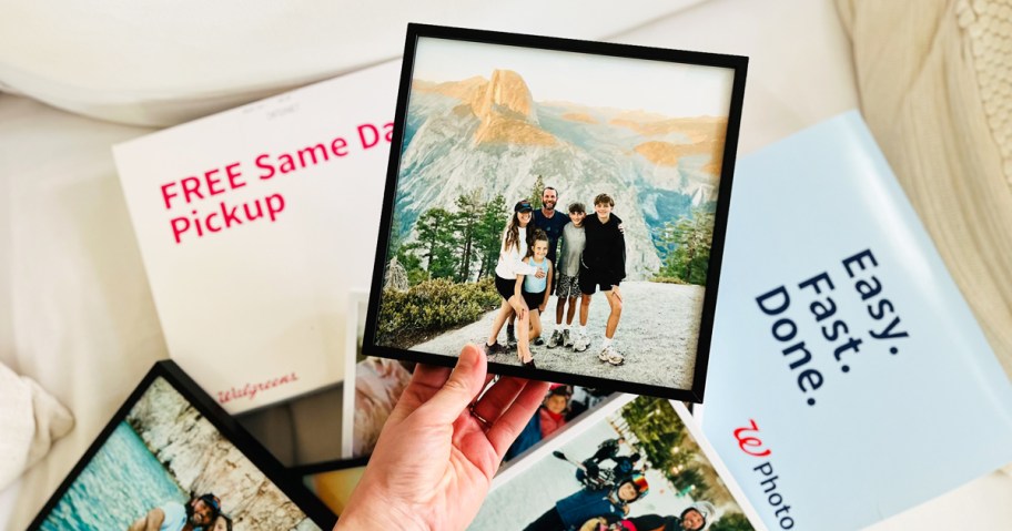 holding a framed family photo above walgreens photo packaging