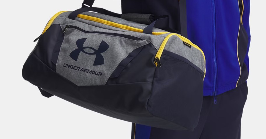 man carrying a grey and black under armour duffle bag