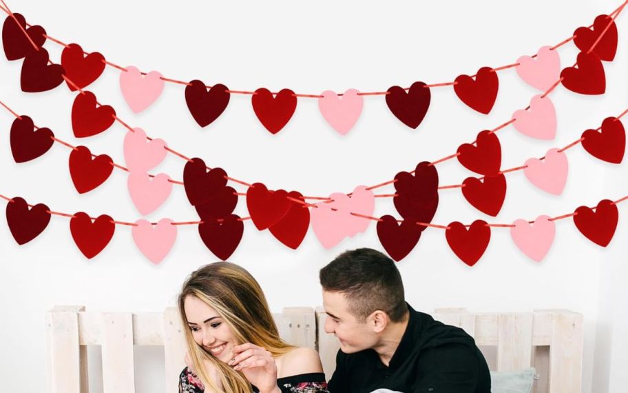 valentines day garland displayed on the wall behind couple