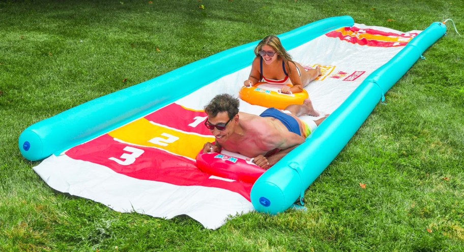 adults sliding down a large slip n slide