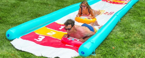 adults sliding down a large slip n slide