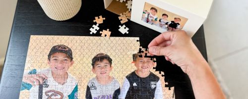 Hand making a Walgreens photo puzzle with children on it