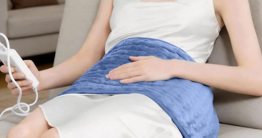Woman using heater on her lap with remote control while lying down