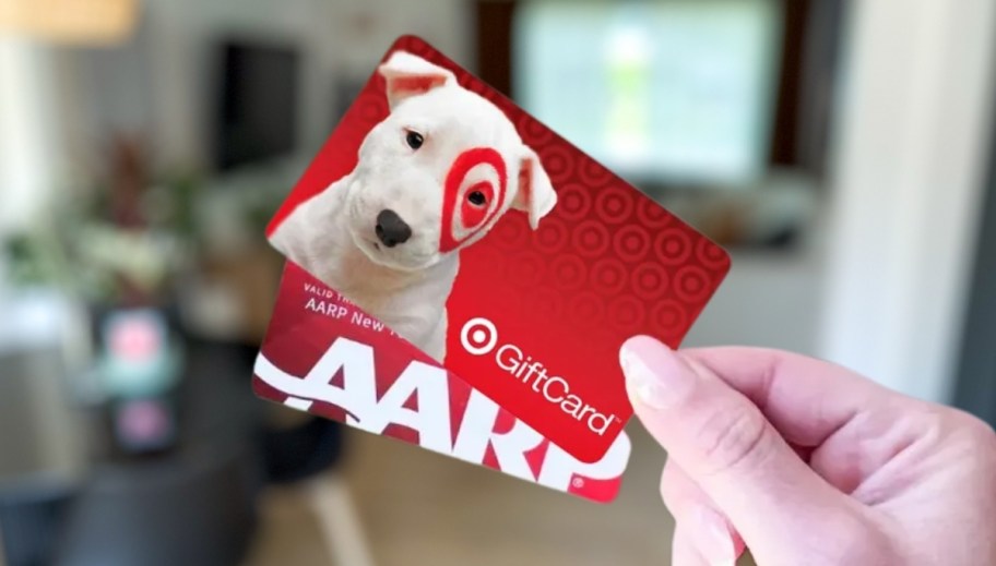 Hand holding Target gift card and AARP membership card