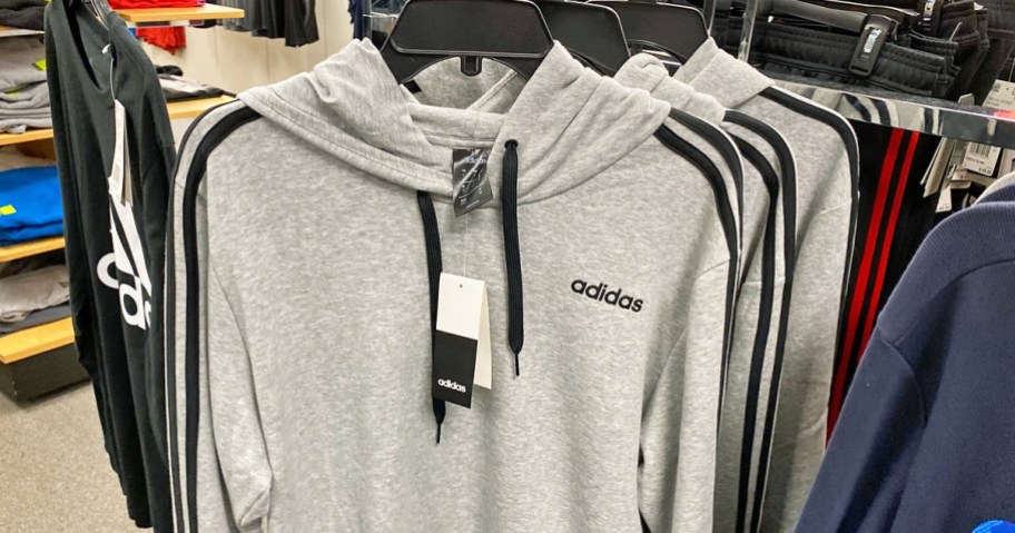 grey and black adidas hoodies on hangers in store