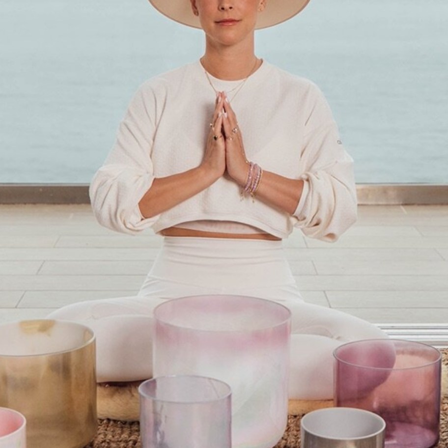 a woman in a hat with palms pressed togther in meditation