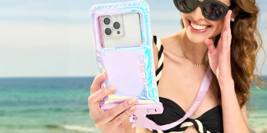 woman holding pink/purple phone case at beach
