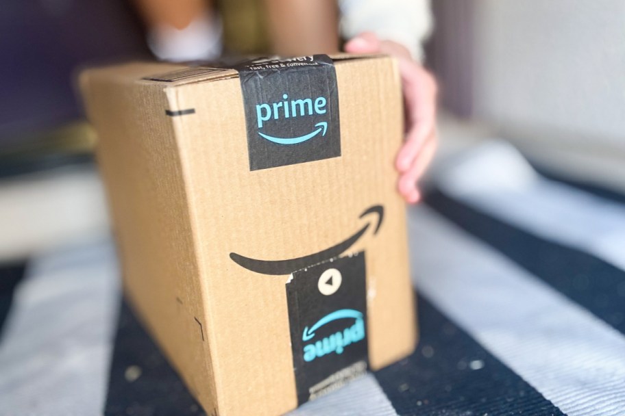 hand grabbing amazon prime box on ground