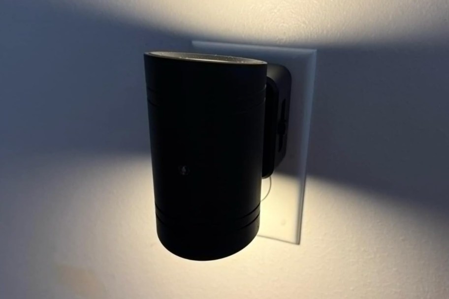 black cylinder night light plugged into wall