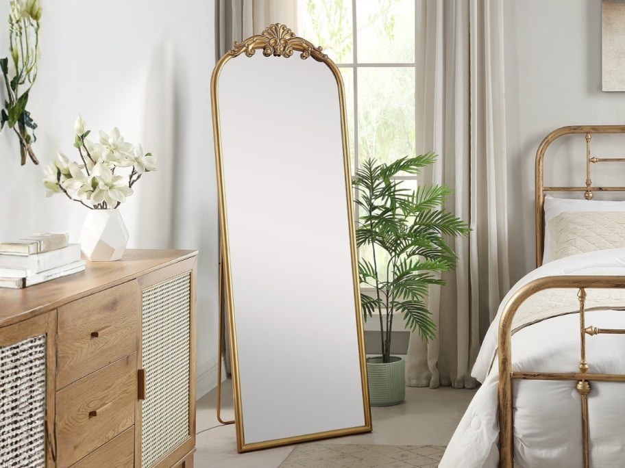 a floor length gold filagree mirror in a bedroom