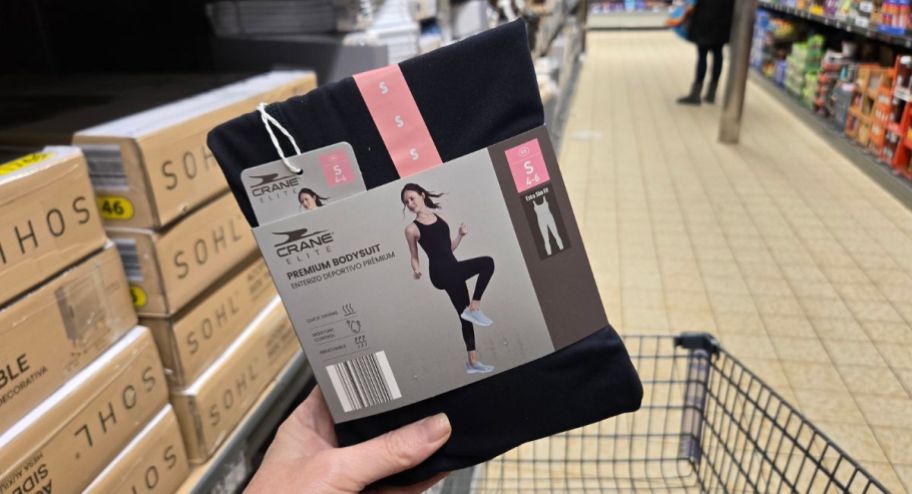 hand holding a black bodysuit with a shopping cart in the background