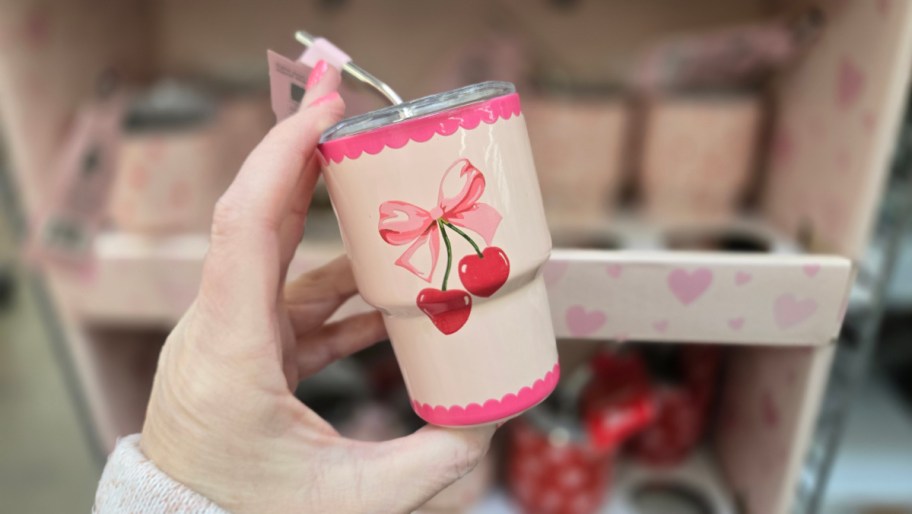 hand holding up a mini tumbler with a bow and cherries on it