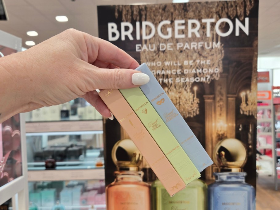 A hand holding up three boxes of Bridgerton perfume at Ulta.