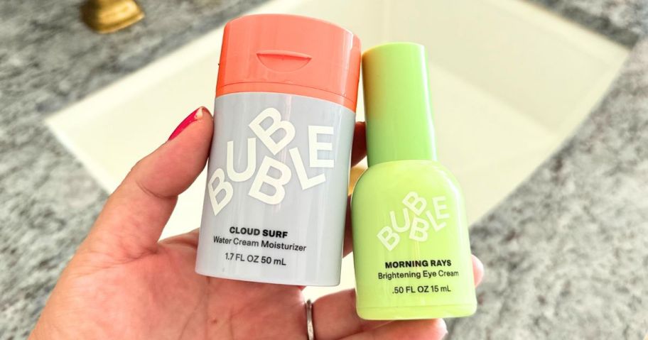 hand holding two bubble skincare products in bathroom
